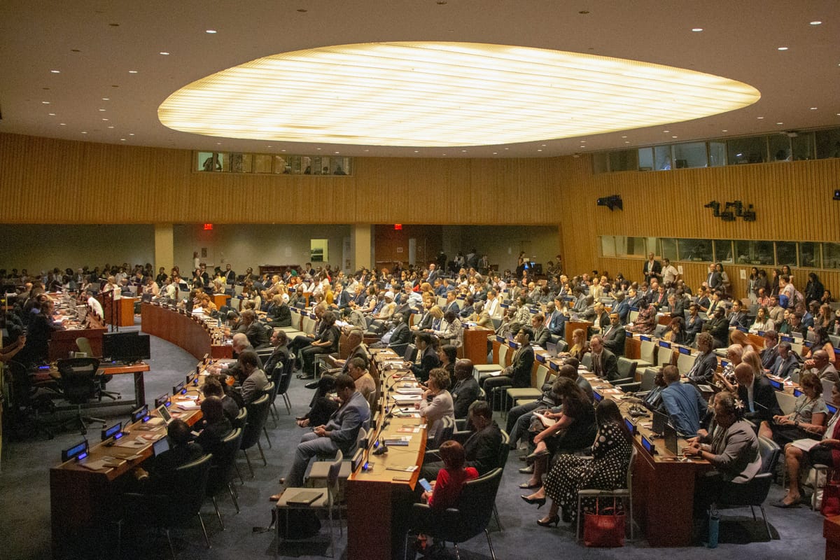 Delegates seated in rows of desks in a large plenary hall.